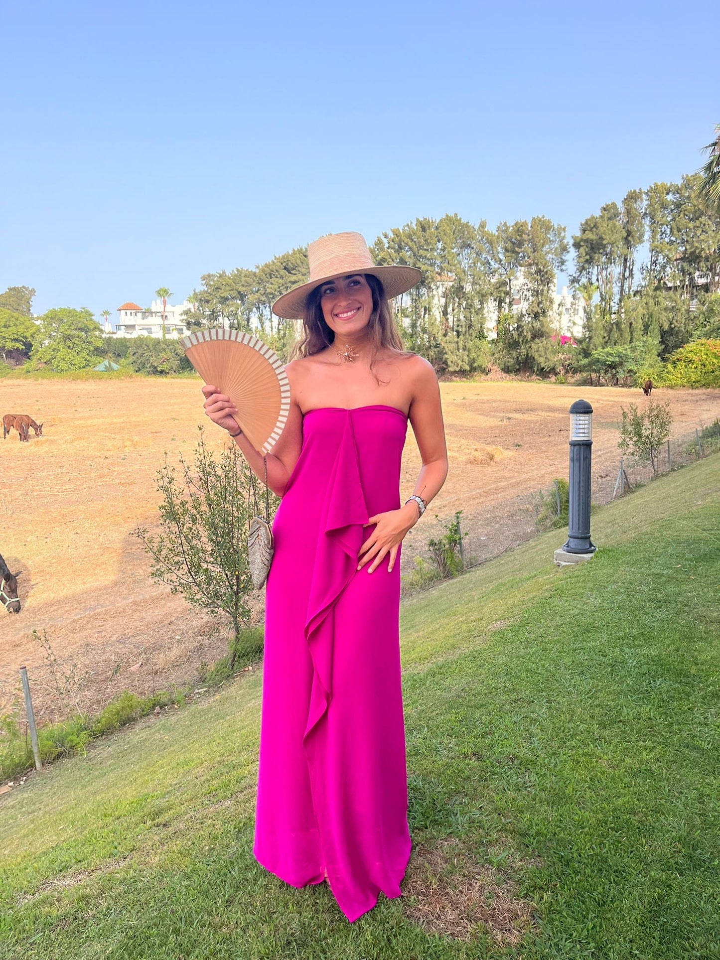 Vestido elegante de color rosa fucsia con volantes en el delante de la marca Zambrana.
